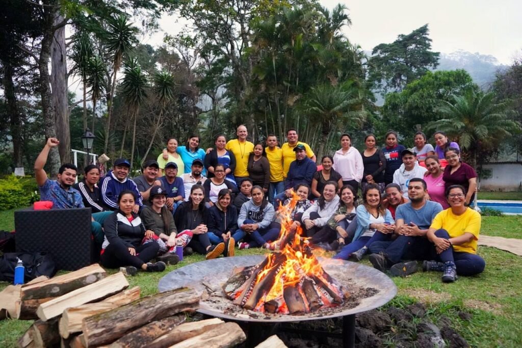 Equipo corporativo compartiendo alrededor de una fogata al cierre de una experiencia Boot Camp de Extremo a Extremo