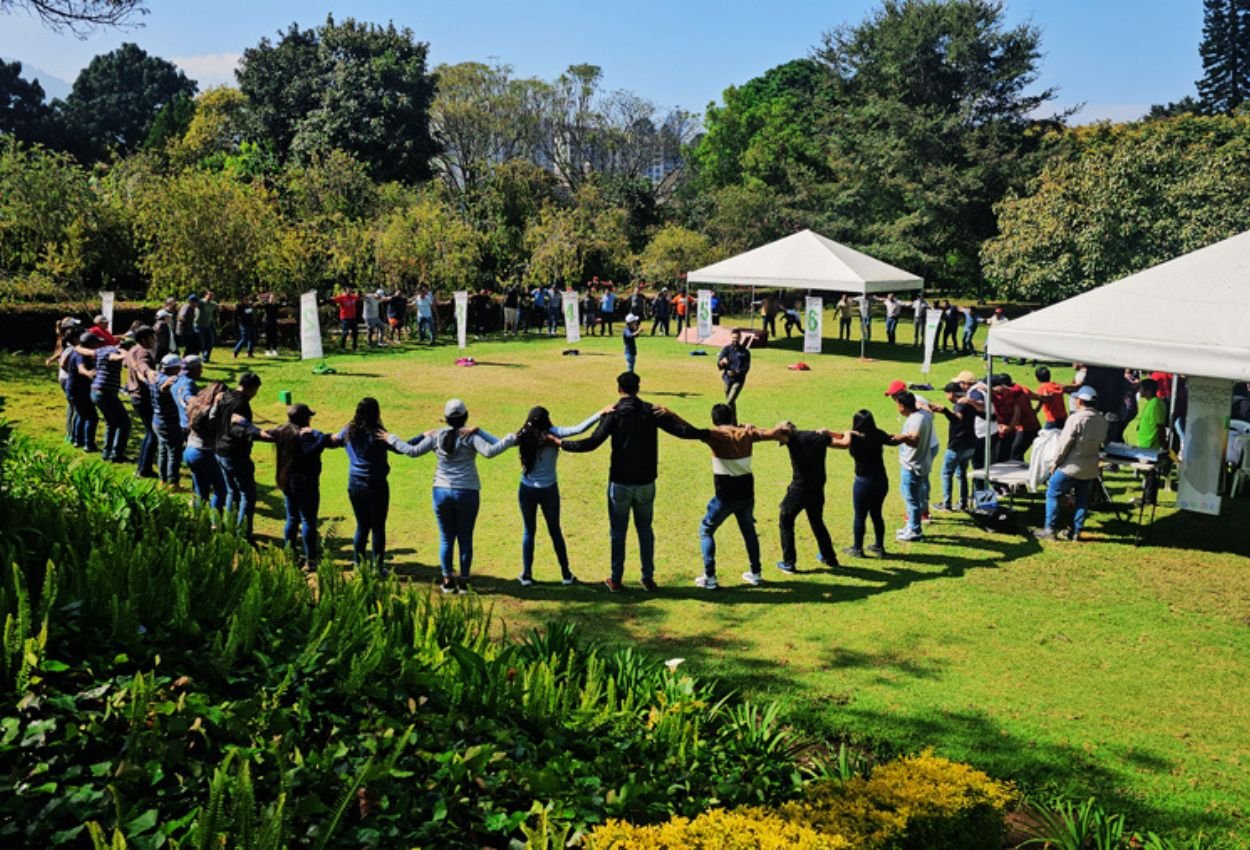 Colaboradores de una empresa guatemalteca en círculo durante un convivio corporativo al aire libre organizado por Extremo a Extremo