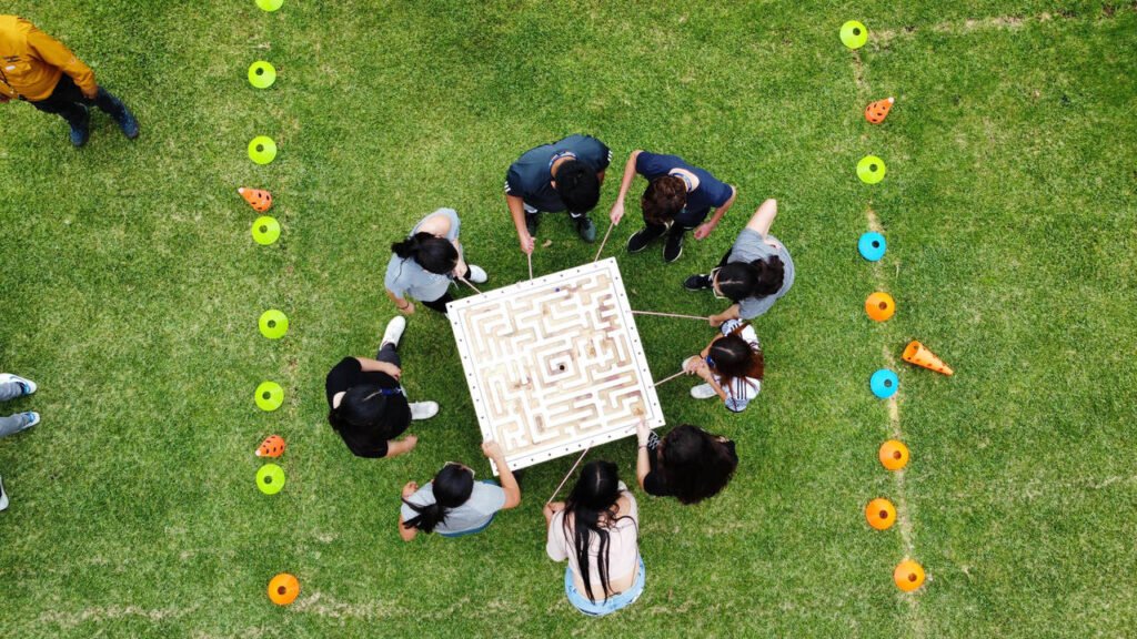 Equipo corporativo resolviendo laberinto de estrategia en conjunto durante actividad de integración