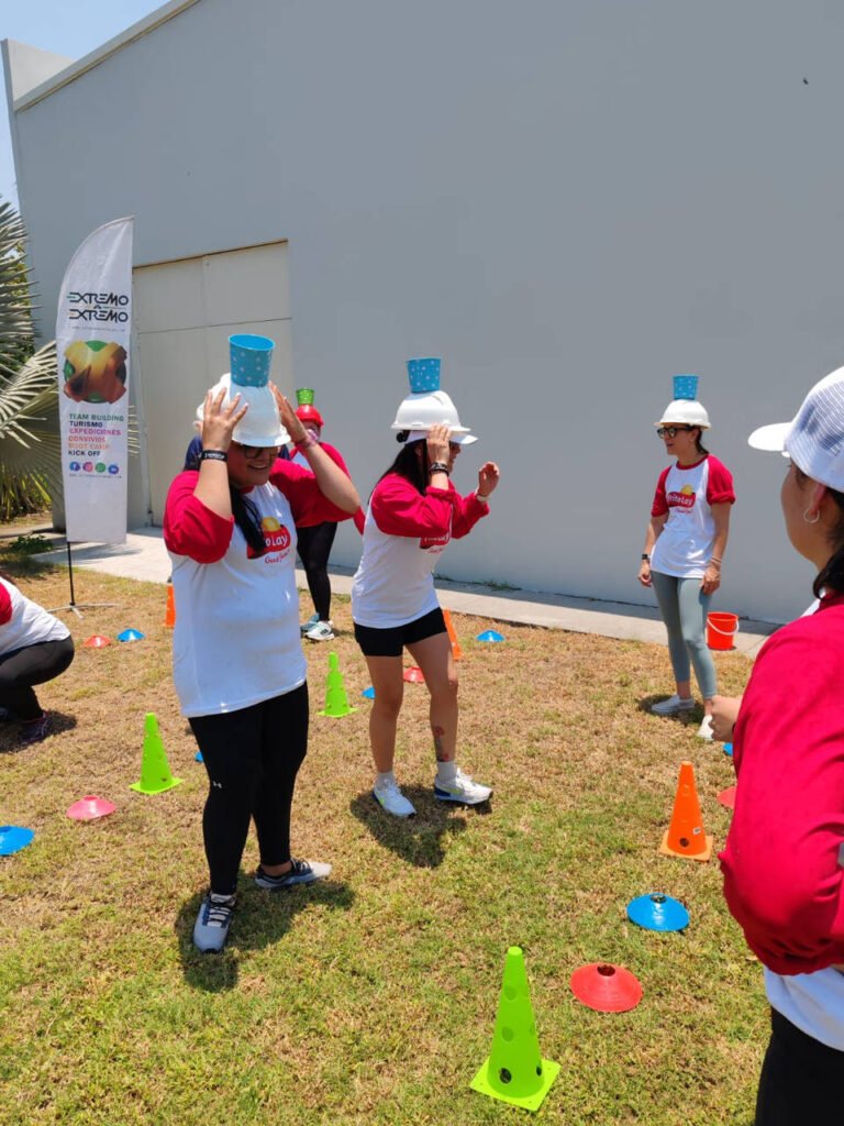 Colaboradores balanceando cubetas de agua durante una jornada de integración corporativa