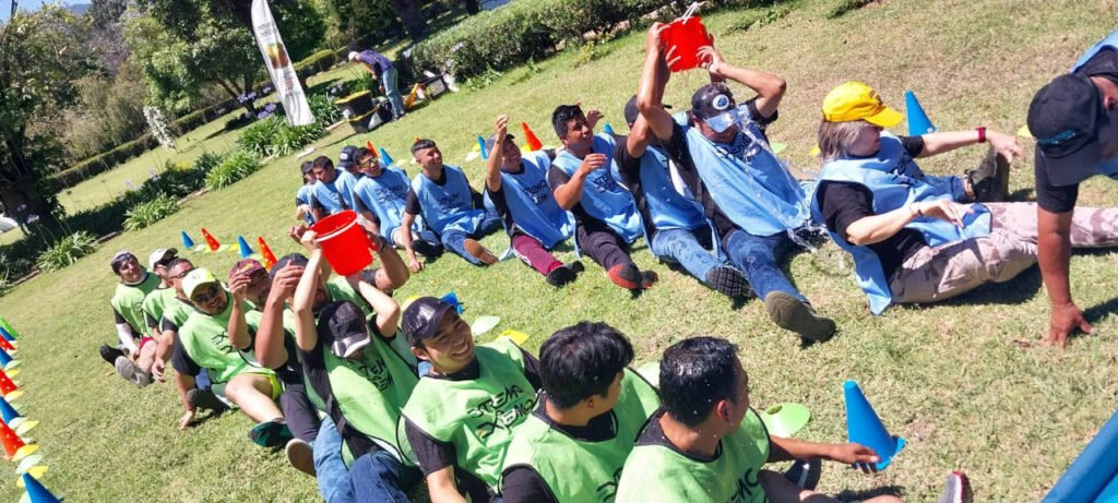 Equipos pasando cubetas de agua en cadena durante una actividad de integración de Splash Day