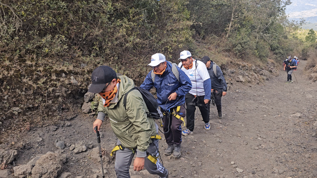 Equipo corporativo avanzando con equipo de seguridad por un sendero de montaña durante un Boot Camp