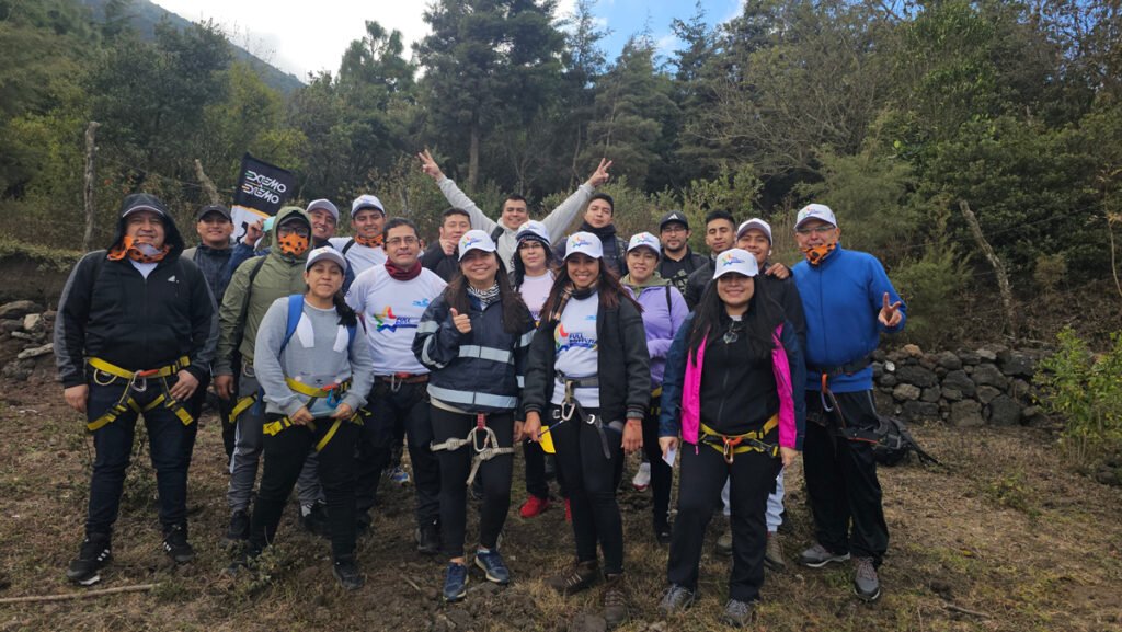 Grupo de colaboradores con arneses preparándose para un reto de cuerdas en un Boot Camp de Extremo a Extremo